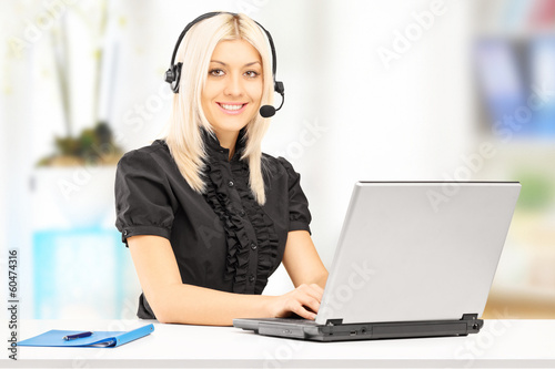 Photo: Young female customer service operator working on laptop Young female customer service operator working on laptop