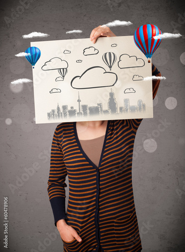 Photo: Woman holding a cardboard with cityscape in front of her head Woman holding a cardboard with cityscape in front of her head