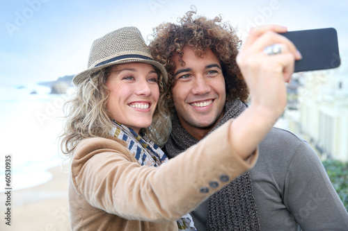 Photo: Cheerful couple taking picture with smartphone Cheerful couple taking picture with smartphone