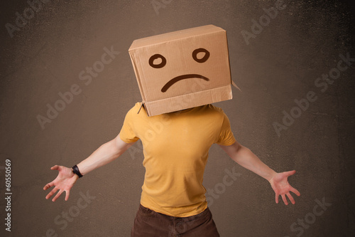 Photo: Young man with a brown cardboard box on his head with sad face Young man with a brown cardboard box on his head with sad face
