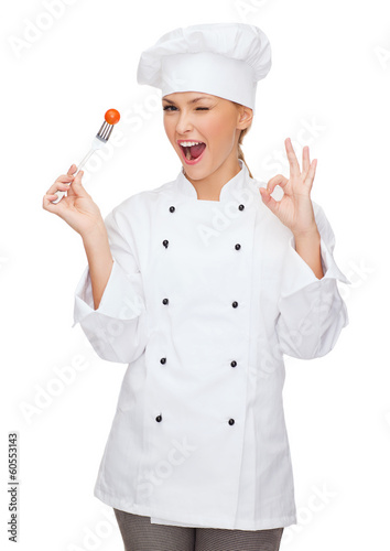 Photo: smiling female chef with fork and tomato smiling female chef with fork and tomato