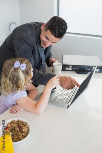 Photo: Businessman pointing at laptop while looking at daughter Businessman pointing at laptop while looking at daughter