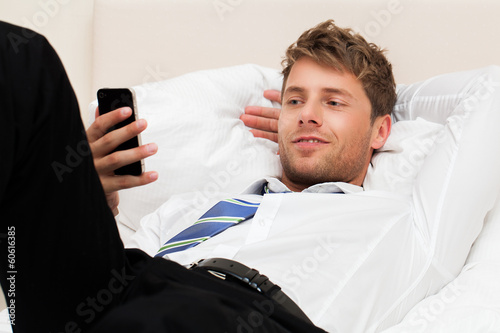 Photo: Geschäftsmann im Hotelbett mit Telefon Geschäftsmann im Hotelbett mit Telefon