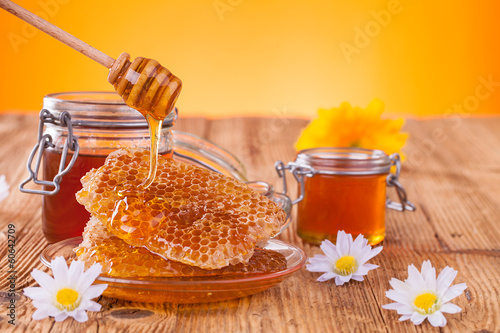 Photo: Honey in jar with honeycomb and wooden drizzler Honey in jar with honeycomb and wooden drizzler
