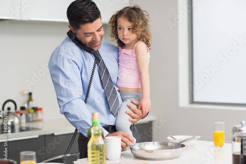 Photo: Well dressed father with daughter preparing food while on call Well dressed father with daughter preparing food while on call