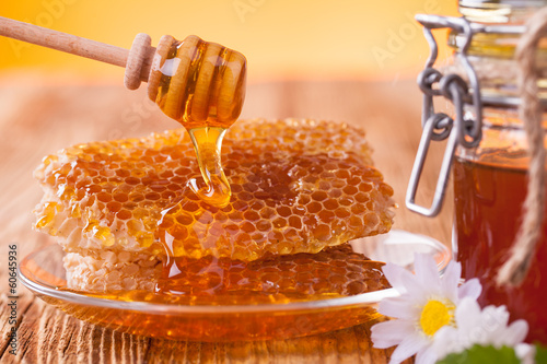Photo: Honey in jar with honeycomb and wooden drizzler Honey in jar with honeycomb and wooden drizzler