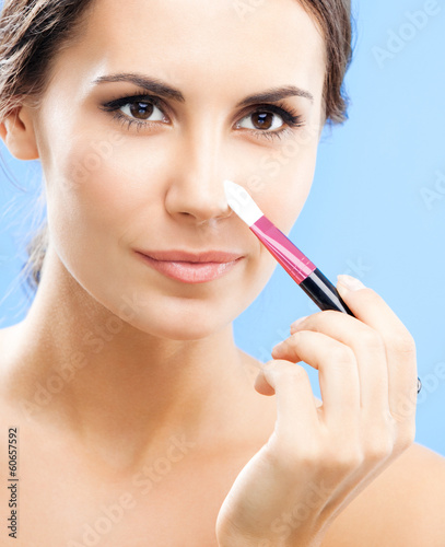 Photo: Woman with cosmetics brush, on blue Woman with cosmetics brush, on blue