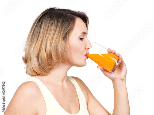 Photo: Profile portrait of a young woman drinks orange juice. Profile portrait of a young woman drinks orange juice.