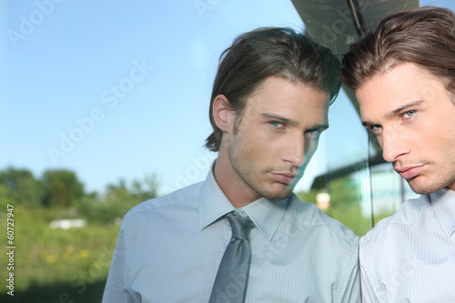 Photo: Young man standing next to a window Young man standing next to a window