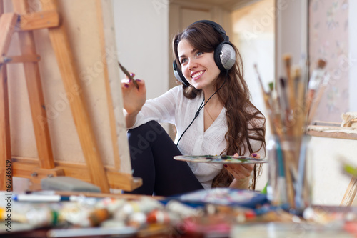 Photo: girl in headphones paints with oil colors on canvas girl in headphones paints with oil colors on canvas