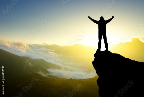 Photo: Silhouette of a winner on the mountain top. Active life concept Silhouette of a winner on the mountain top. Active life concept
