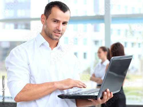 Photo: Portrait of a smart business man using laptop with colleagues Portrait of a smart business man using laptop with colleagues