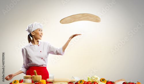 Photo: Asian female cook making pizza Asian female cook making pizza