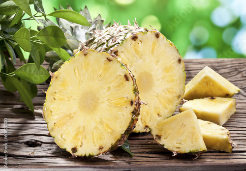 Photo: Pineapple with slices on a wooden table. Pineapple with slices on a wooden table.