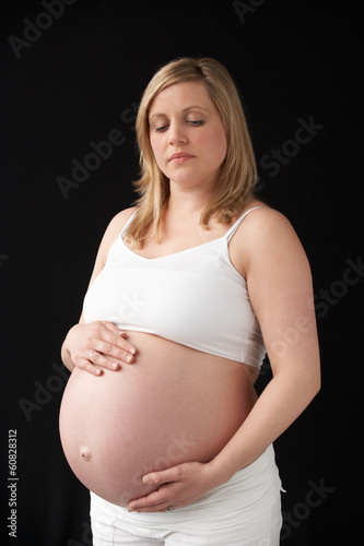 Photo: Portrait Of 9 months Pregnant Woman Wearing White On Black Backg Portrait Of 9 months Pregnant Woman Wearing White On Black Backg