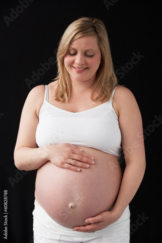 Photo: Portrait Of 9 months Pregnant Woman Wearing White On Black Backg Portrait Of 9 months Pregnant Woman Wearing White On Black Backg
