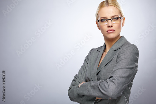 Photo: Portrait of a beautiful young business woman standing against gr Portrait of a beautiful young business woman standing against gr