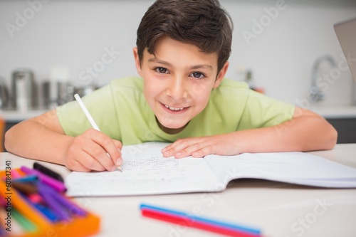 Photo: Smiling boy doing homework in kitchen Smiling boy doing homework in kitchen