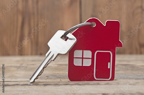 Photo: Symbol of the house with silver key on wooden background Symbol of the house with silver key on wooden background