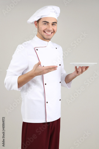 Photo: Professional chef in white uniform and hat, on gray background Professional chef in white uniform and hat, on gray background