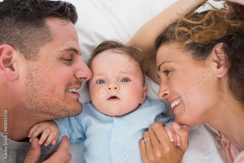 Photo: Cute baby with parents in bed Cute baby with parents in bed