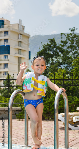 Photo: Happy little boy waving at the camera poolside Happy little boy waving at the camera poolside