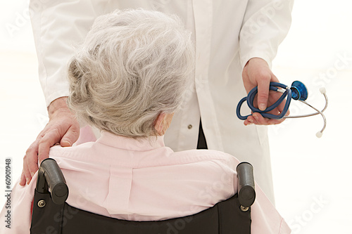 Photo: caring doctor with disabled senior patient back view caring doctor with disabled senior patient back view