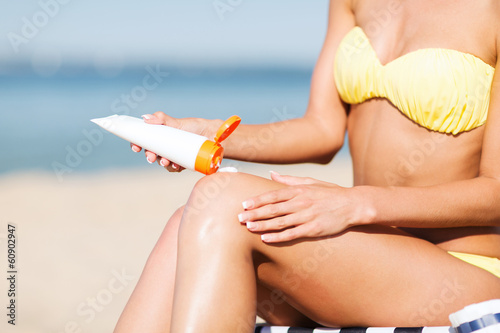 Photo: girl putting sun protection cream on beach chair girl putting sun protection cream on beach chair
