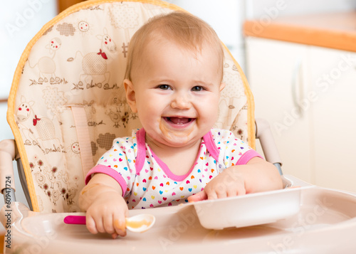 Photo: smiling baby eating food on kitchen smiling baby eating food on kitchen