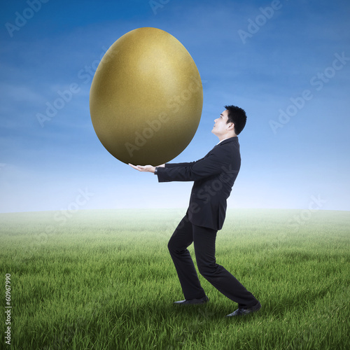 Photo: Businessman holding a golden egg Businessman holding a golden egg