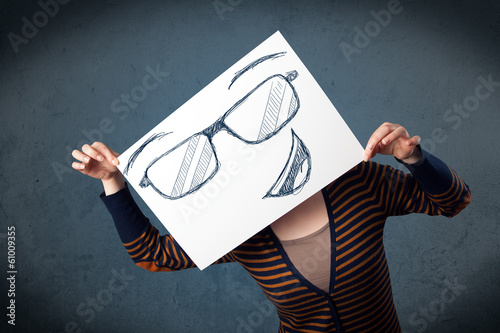 Photo: Woman holding a paper with smiley face in front of her head Woman holding a paper with smiley face in front of her head