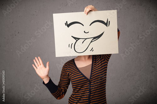 Photo: Woman holding a paper with cute smiley face on it in front of he Woman holding a paper with cute smiley face on it in front of he