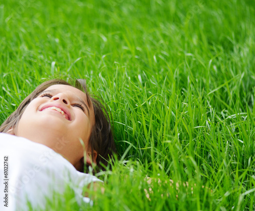 Photo: Happy little boy enjoying on grass field and dreaming Happy little boy enjoying on grass field and dreaming