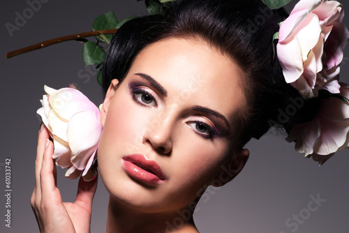 Photo: Closeup portrait of beautiful young woman with pink flowers in h Closeup portrait of beautiful young woman with pink flowers in h