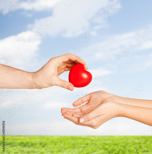 Photo: man hand giving red heart to woman man hand giving red heart to woman