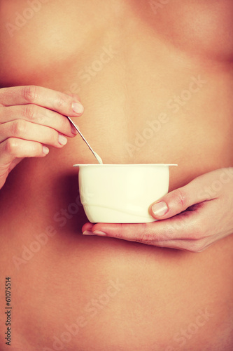 Photo: Naked young beautiful woman is eating yogurt. Naked young beautiful woman is eating yogurt.