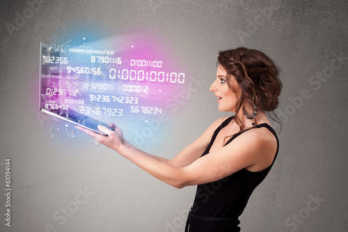 Photo: Casual woman holding laptop with exploding data and numers Casual woman holding laptop with exploding data and numers