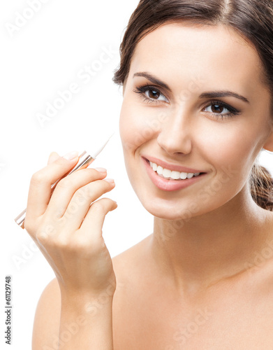Photo: Smiling woman applying concealer on face, isolated Smiling woman applying concealer on face, isolated