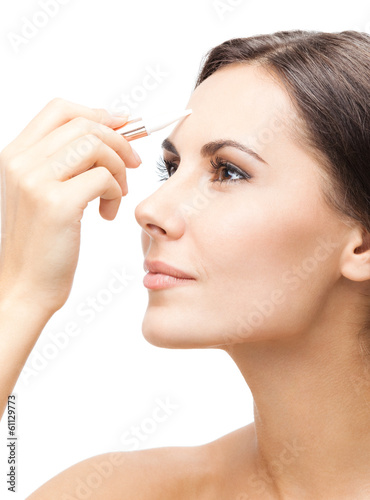 Photo: Smiling woman applying concealer on face, isolated Smiling woman applying concealer on face, isolated