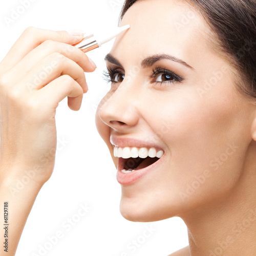 Photo: Smiling woman applying concealer on face, isolated Smiling woman applying concealer on face, isolated