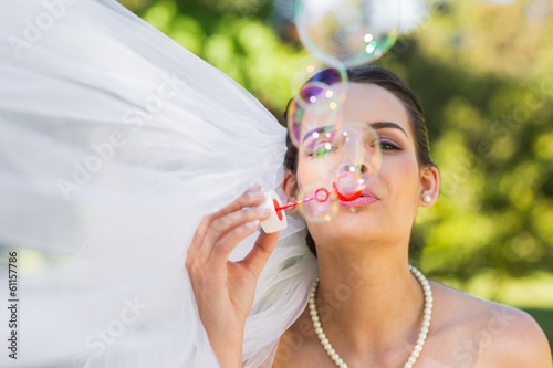 Photo: Bride blowing soap bubbles in park Bride blowing soap bubbles in park
