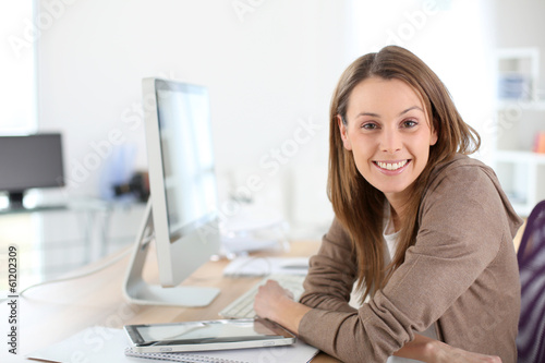 Photo: Smiling woman in office sitting at desktop Smiling woman in office sitting at desktop