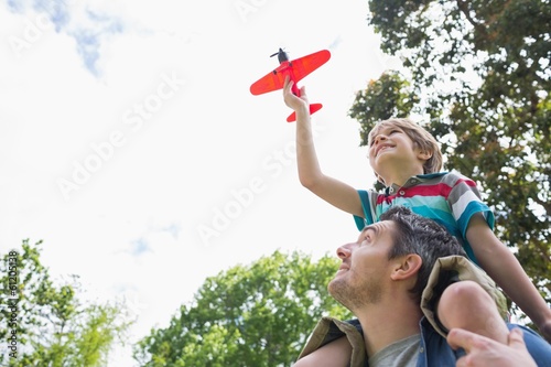Photo: Boy with toy aeroplane sitting on father's shoulders Boy with toy aeroplane sitting on father's shoulders