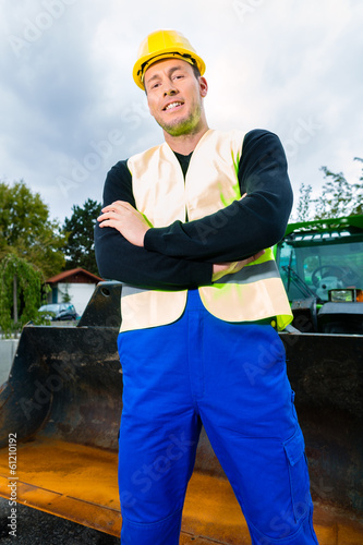 Photo: Bauarbeiter vor Baumaschine einer Baustelle Bauarbeiter vor Baumaschine einer Baustelle
