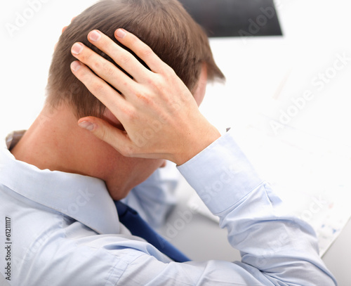 Photo: A businessman with a headache, sitting at the desk. A businessman with a headache, sitting at the desk.