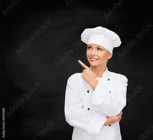 Photo: smiling female chef pointing finger to something smiling female chef pointing finger to something