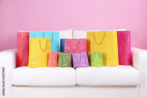 Photo: Colorful shopping bags on sofa, on color wall background Colorful shopping bags on sofa, on color wall background