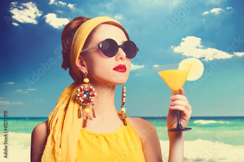 Pretty redhead women with cocktail on the beach.