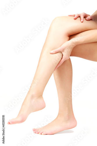 Photo: Pain in a leg, woman holding sore shin, white background Pain in a leg, woman holding sore shin, white background