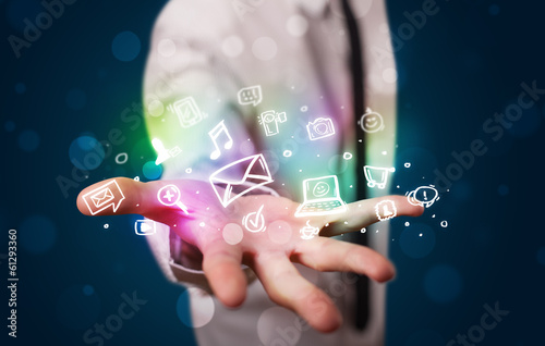 Photo: Young businessman presenting colorful glowing social media icons Young businessman presenting colorful glowing social media icons
